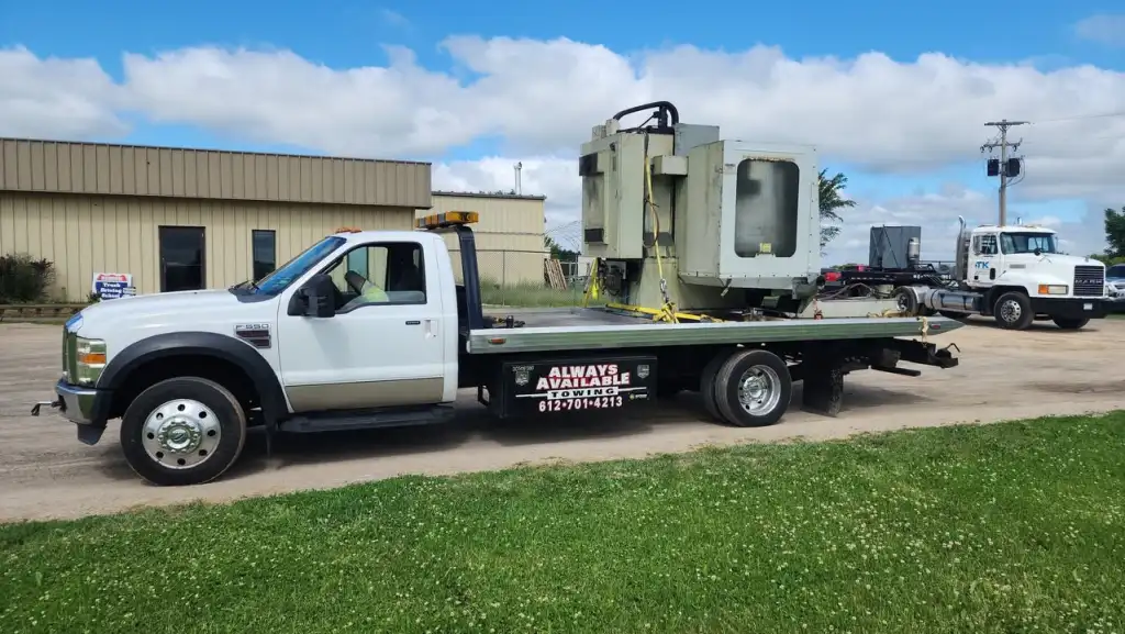 A Always Available Towing white flatbed tow truck carrying equipment, with 612-701-4213 displayed on its side